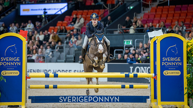 Ponny och ryttare som hoppar över hinder.