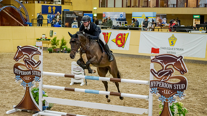 Häst som hoppar över hinder med häst på ryttare.