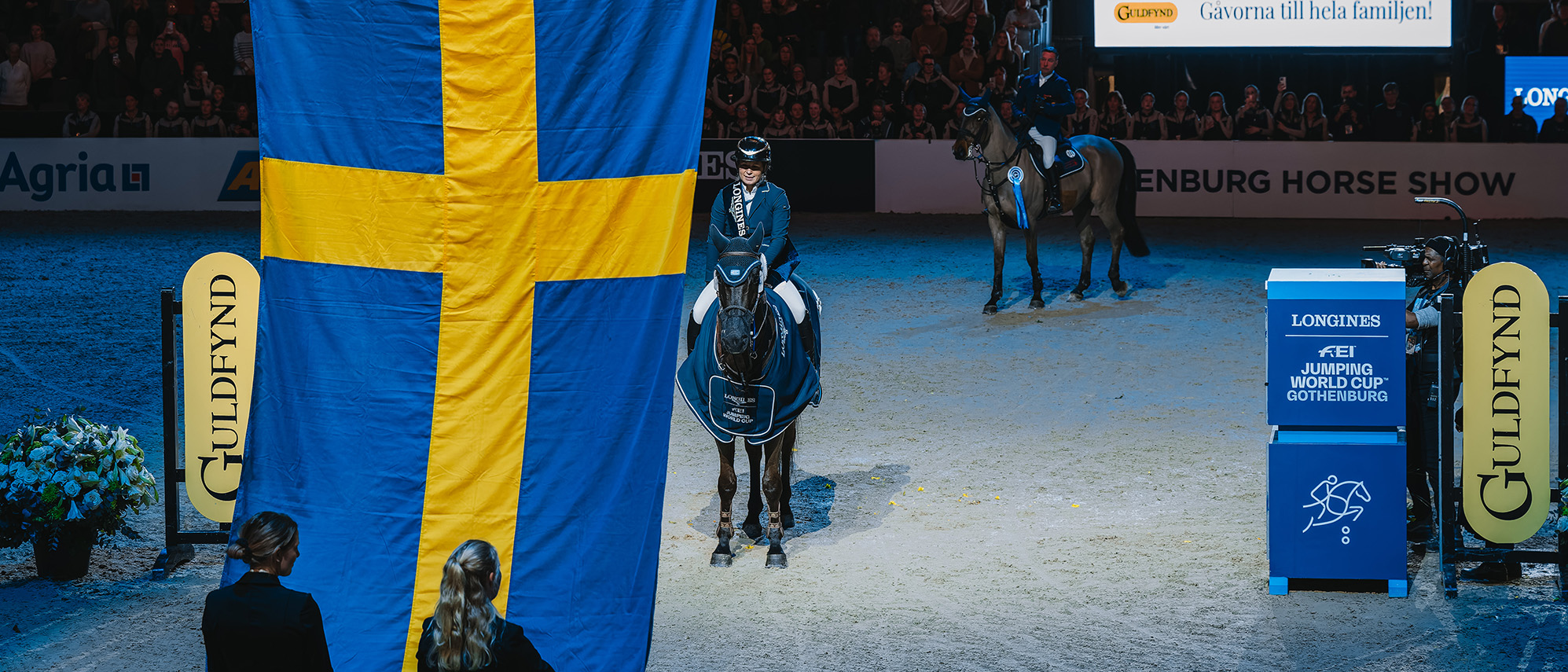 Ryttare och häst på prisutdelning med svensk flagga som hissas. 