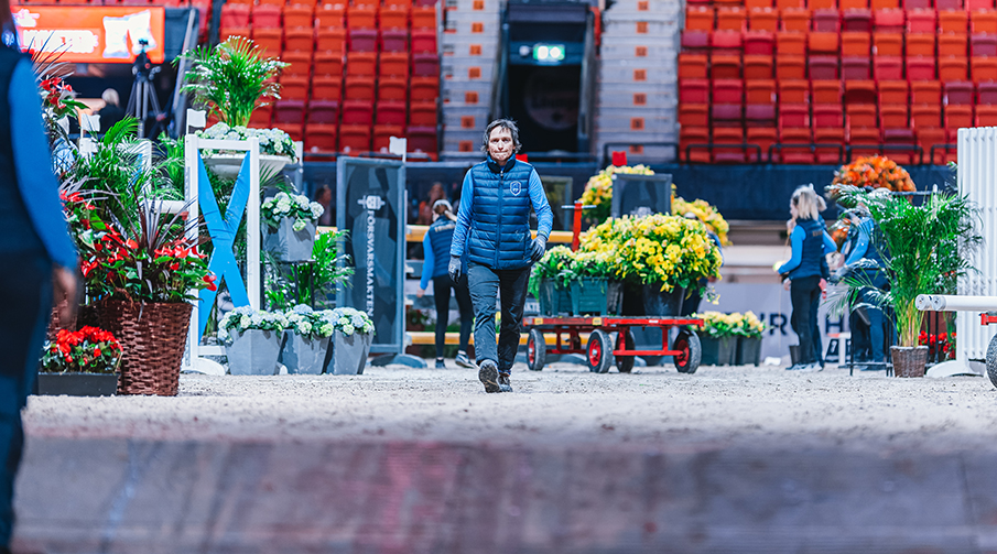 Funktionär på arenan under uppbyggnad av banan med blommor och hinder. 