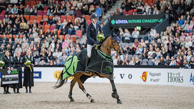 Häst som galopperar med ryttare på ryggen under prisutdelning.